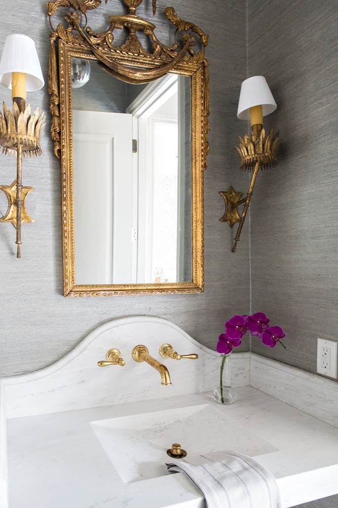 grey and gold bathroom with stunning antique mirror sconces and pedestal sink