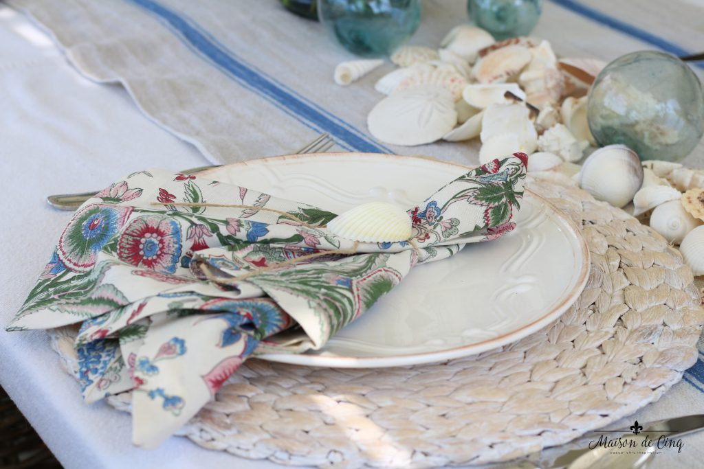 coastal tablescape willow charger white plate floral napkin shells blue striped runner