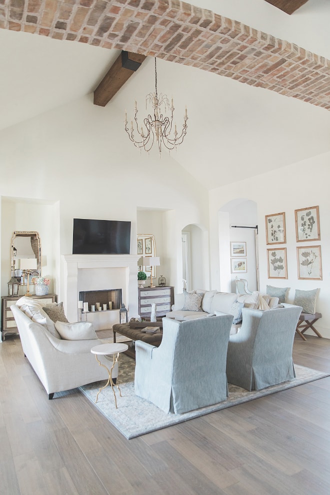 French farmhouse style home living room with brick archway blue linen chairs and french chandelier 