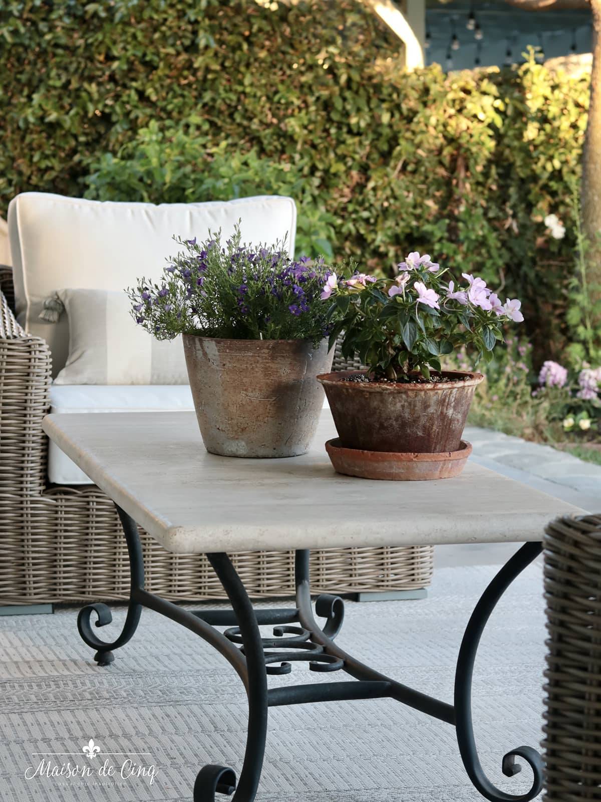 gorgeous French country style outdoor space with travertine table and wicker chairs 