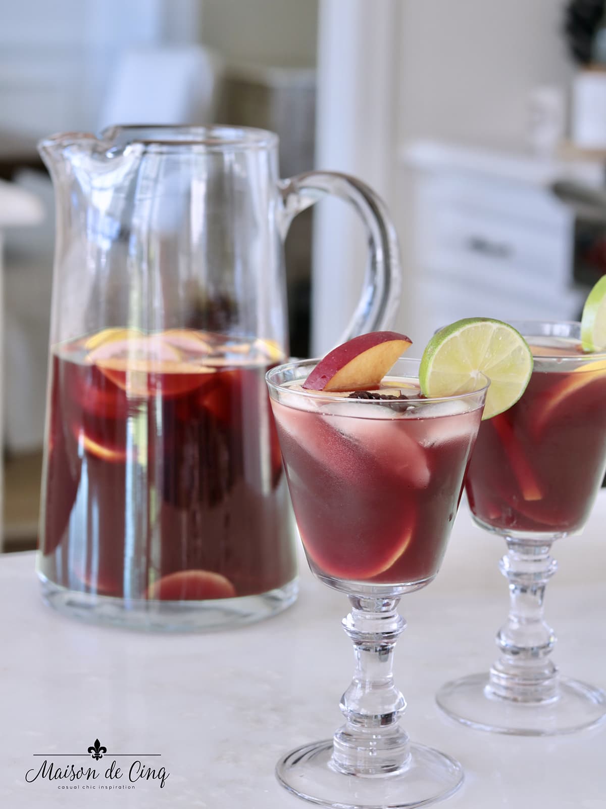red wine sangria with fruit in two glasses and pitcher in white kitchen