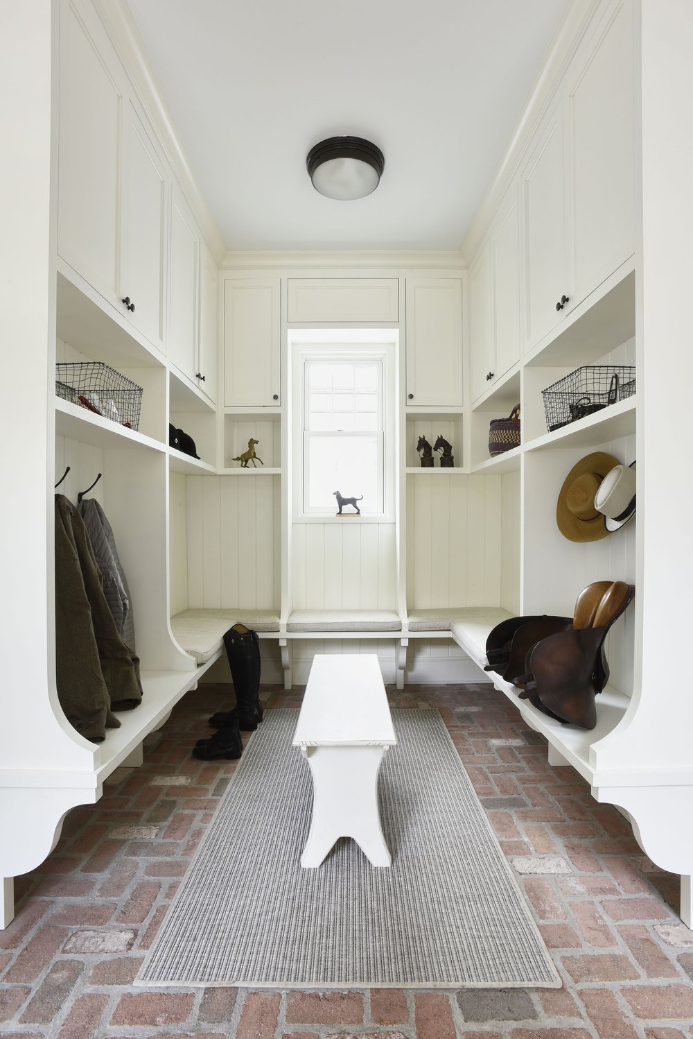 giant farmhouse style mudroom with lots of cabinets and storage and brick floors 