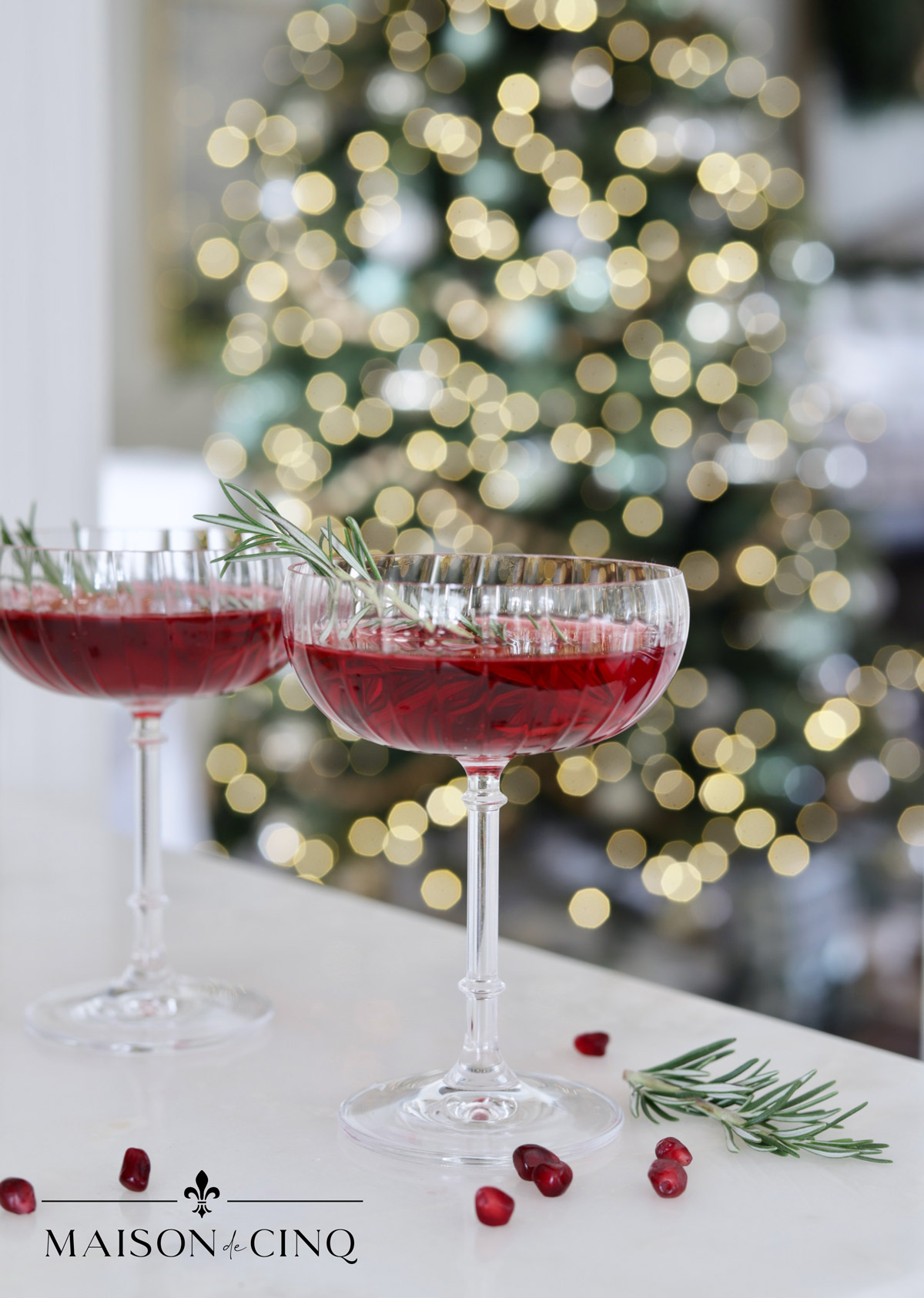 pomegranate gimlet gorgeous red christmas cocktail in coupe glasses by christmas tree 