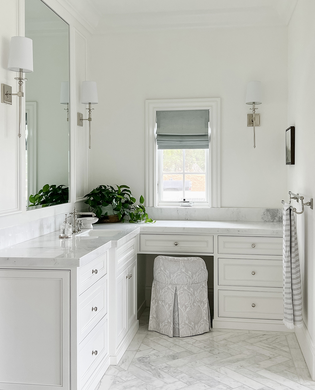 beautiful French inspired bathroom with sage green roman shade and marble herringbone floors