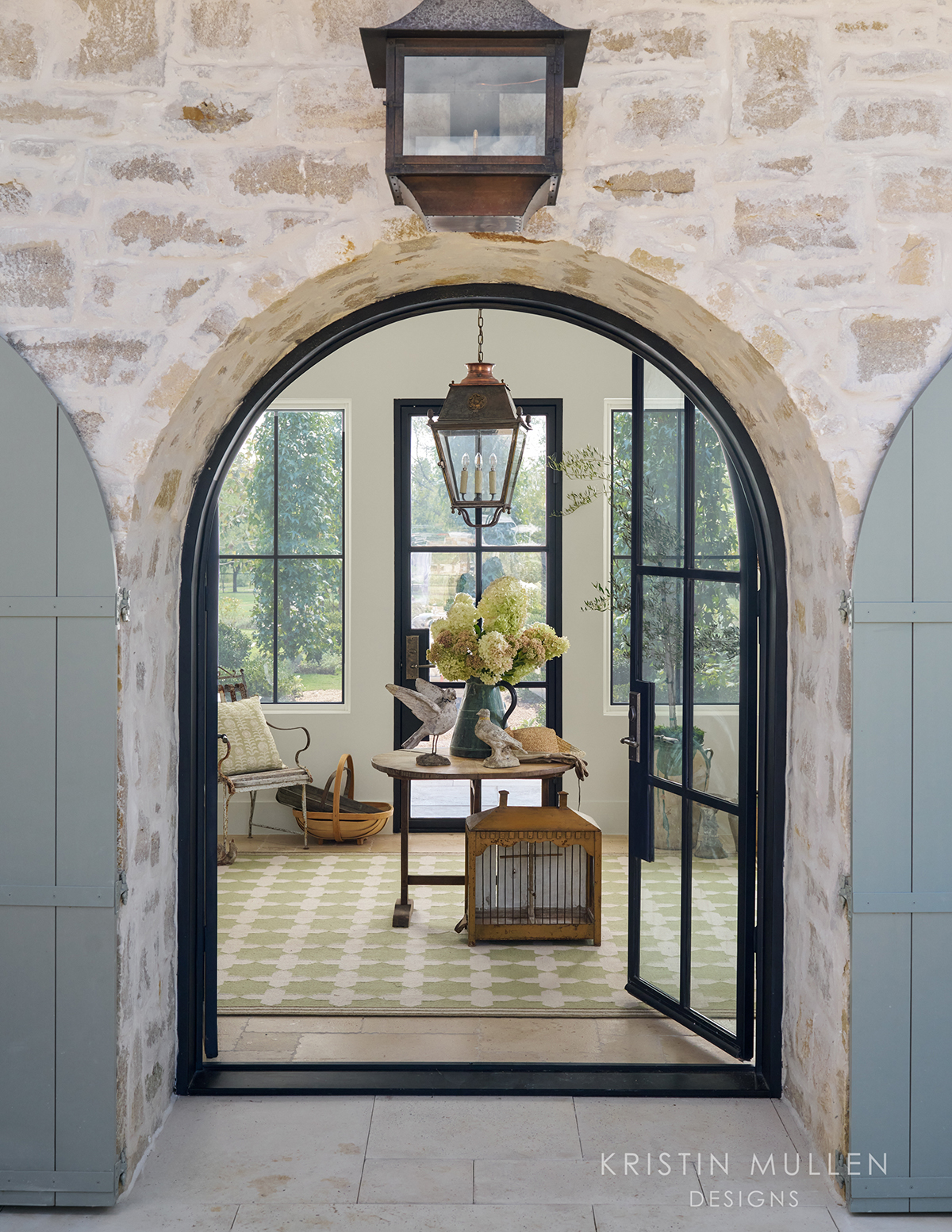 gorgeous entry way with overgrouted stone, an archway and pale French blue doors rustic European style
