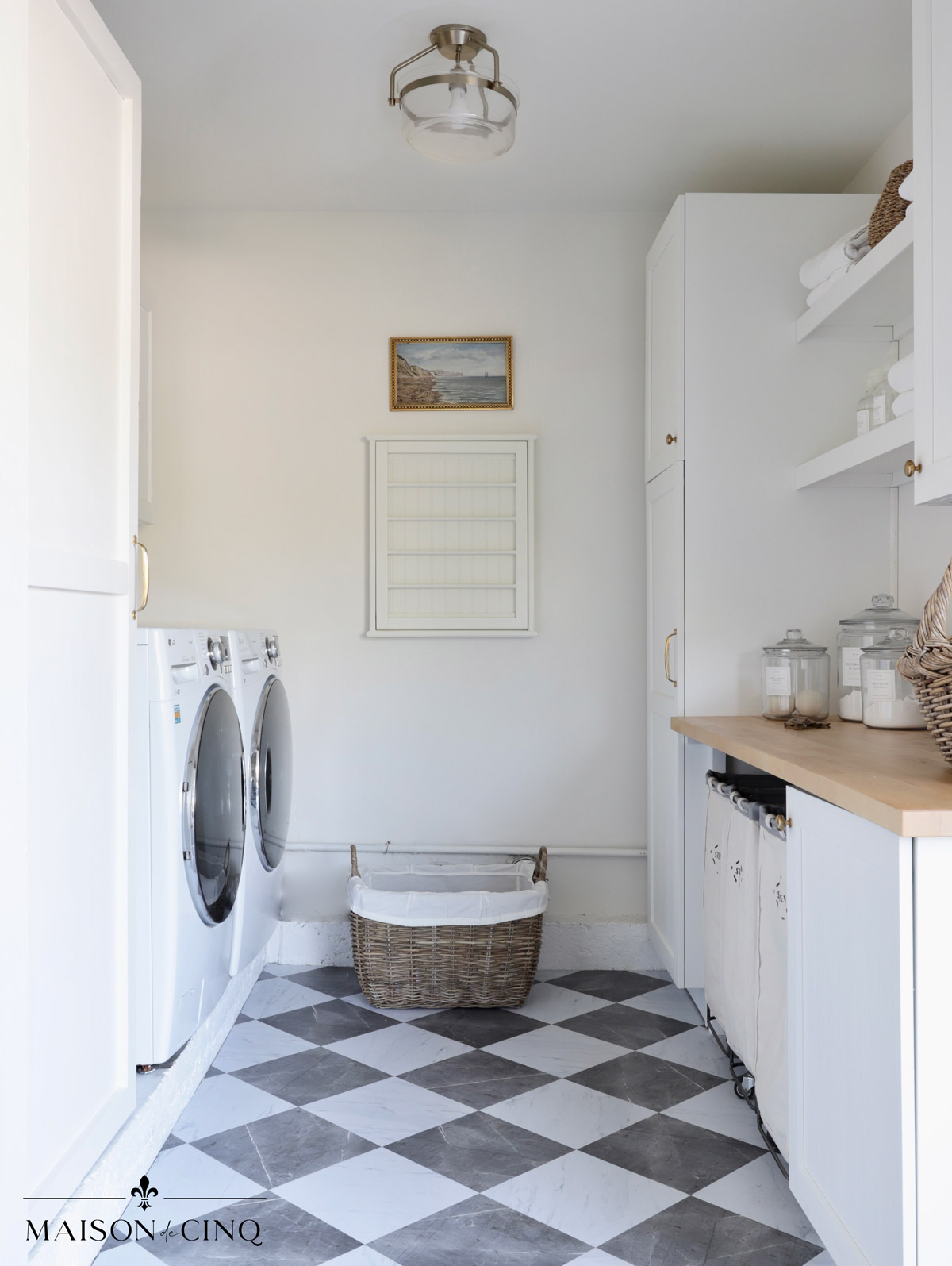gorgeous farmhouse style laundry room with white cabinets checkerboard floors and butcher block counters 
