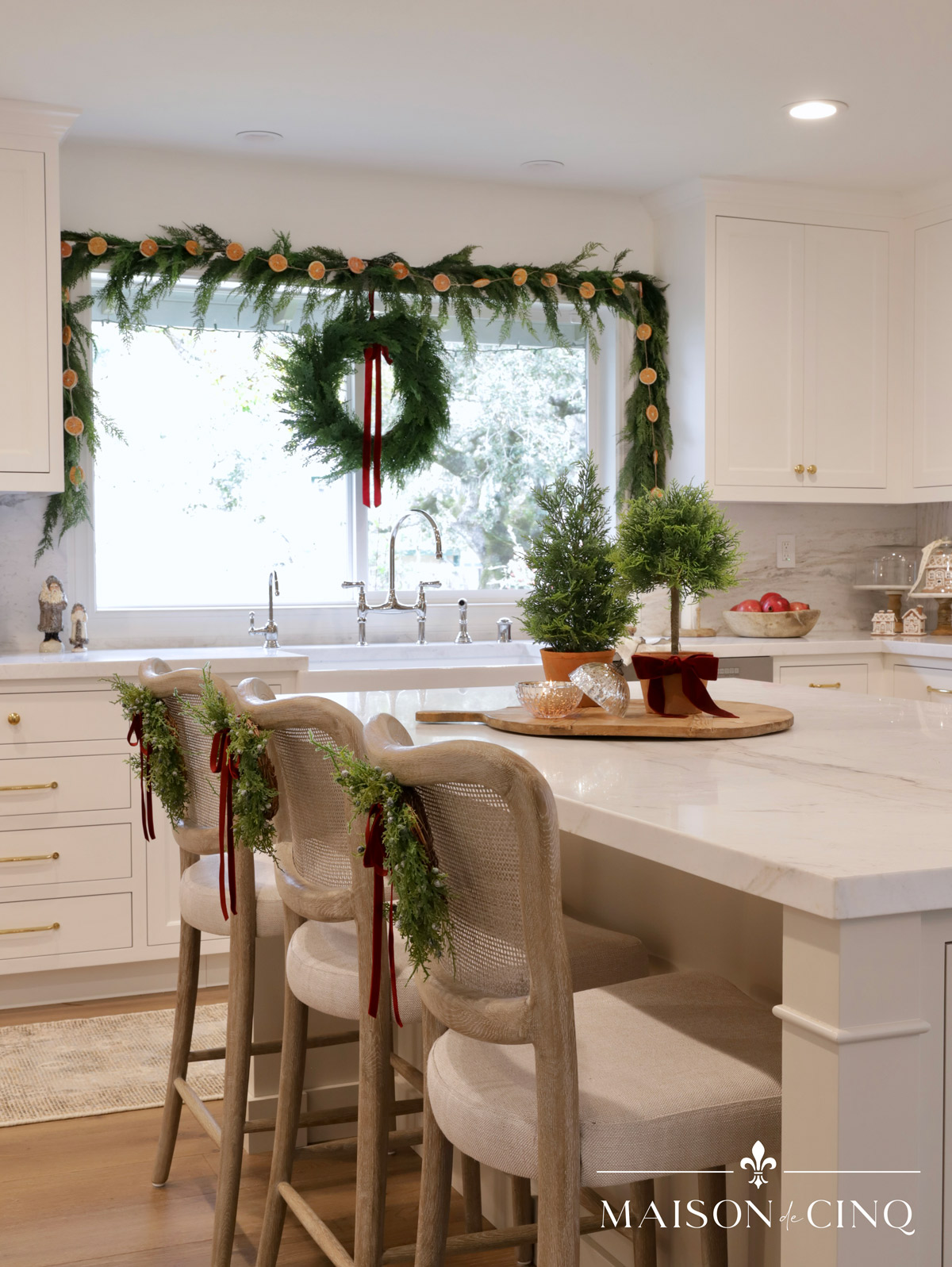 European-inspired Christmas tour in gorgeous white kitchen with garland around the window wreaths on counter stools 