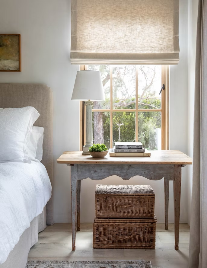 pretty french-inspired bedroom with baskets and roman shade